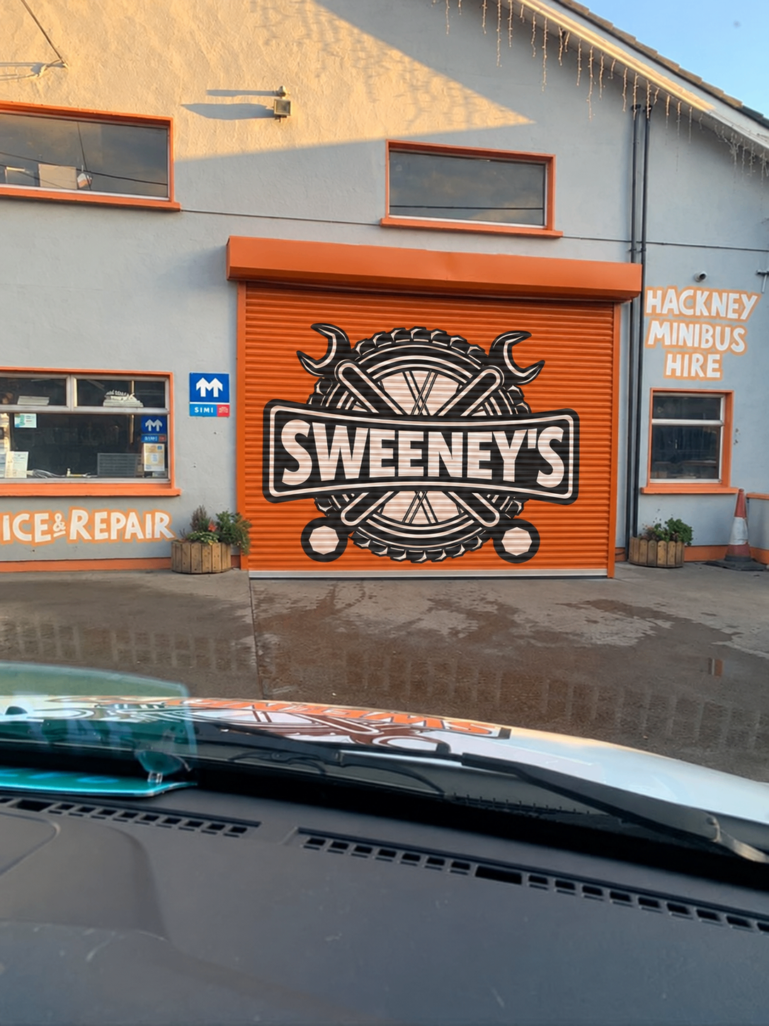 Sweeney’s Garage building with the large Sweeney’s logo on its orange shutter